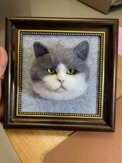 Head Framed 3D wool felt art of a gray and white cat's face with green eyes, displayed on a wooden table